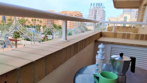 Un balcon offrant une vue sur le paysage urbain, avec des bâtiments et une structure métallique décorative.