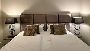 A neatly made bed with a headboard, two bedside lamps, and several pillows. - Heefkant HK/01 - Heefkant (Sylt)