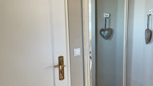 A hallway with a white door, a large mirror, and a metal bucket on the floor. - Heefkant HK/01 - Heefkant (Sylt)