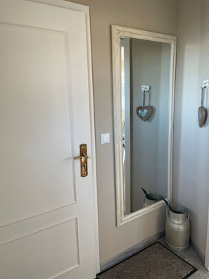 A hallway with a white door, a large mirror, and a metal bucket on the floor. - Heefkant HK/01 - Heefkant (Sylt)