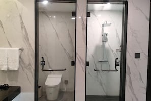 Een moderne badkamer met glazen scheidingswand, toilet, douchegedeelte en handdoekrek.