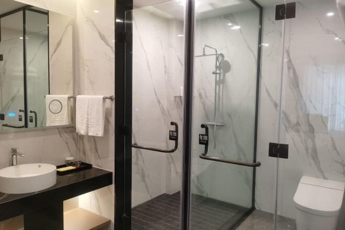 Uma casa de banho moderna com cabine de duche em vidro, lavatório redondo e sanita.