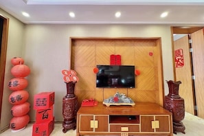 Een kamer met een houten tv-meubel, een flatscreen-televisie en traditionele rode lantaarns.