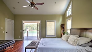 Un dormitorio con cama, banca, ventilador de techo y vistas al exterior.