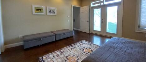 Une chambre spacieuse avec un grand lit, un banc et un tapis.