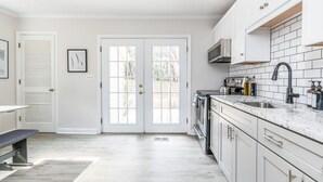 A modern kitchen with white cabinets, a granite countertop, and a built-in oven.