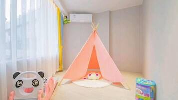 A room with a pink tent, a toy car, and a toy box.