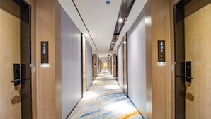 A hotel corridor with wooden walls, numbered doors, and a patterned carpet. - Longquan Hotel (Nandaqiao Flagship) (Haikou)