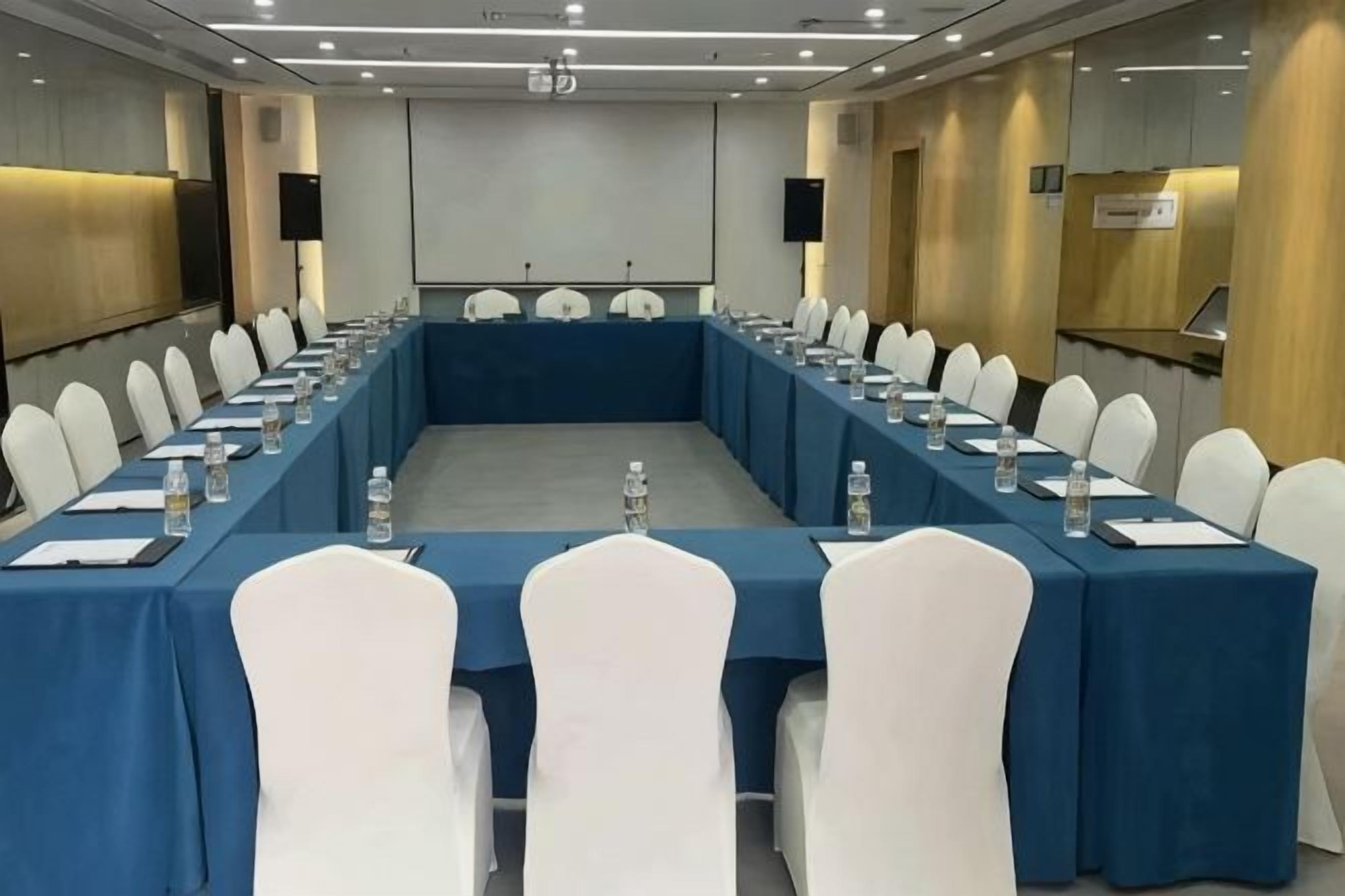 A conference room with a long table, white chairs, and water bottles.
