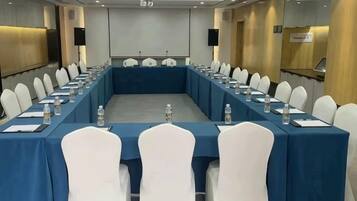 A conference room with a long table, white chairs, and water bottles.