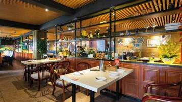 A restaurant interior with wooden ceiling, tables, chairs, and a bar area with shelves.