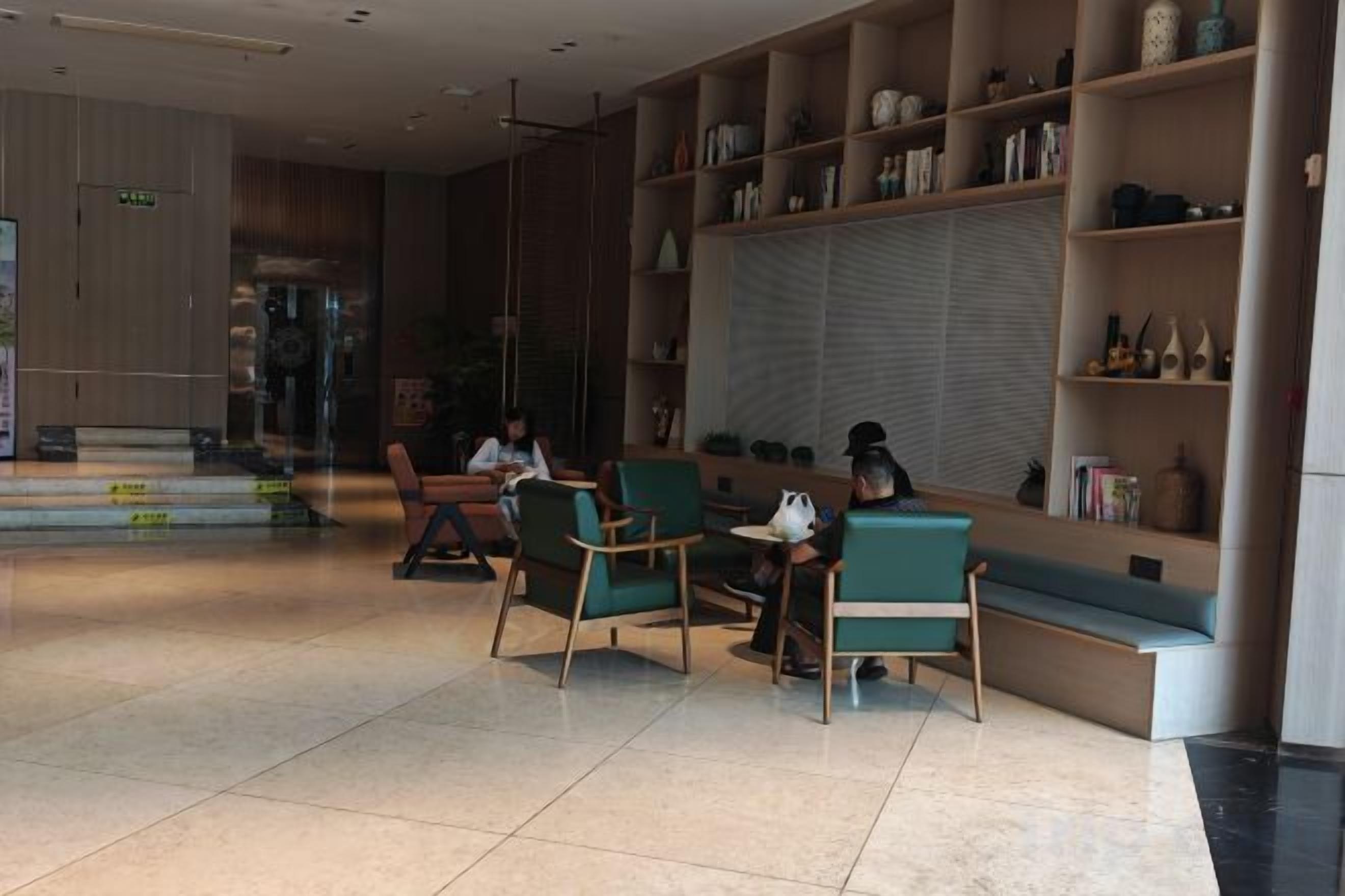 A modern interior with seating areas, a reception desk, and a bookshelf.