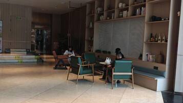 A modern interior with seating areas, a reception desk, and a bookshelf.