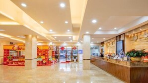 A hotel lobby with a reception desk, a food kiosk, and a clean, well-lit interior. - Longquan Hotel (Nandaqiao Flagship) (Haikou)