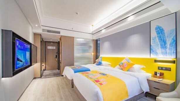 A modern hotel room with a large bed, a bedside table, a TV mounted on the wall, and a painting on the wall. - Longquan Hotel (Nandaqiao Flagship) (Haikou)