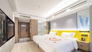 A modern hotel room with a large bed, a bedside table, a TV, and a large window.