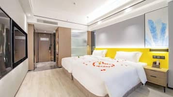 Una habitación de hotel moderna con una cama grande, una mesita de noche, un televisor y un ventanal amplio.