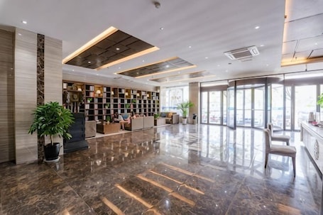 A spacious lobby with a polished marble floor, a reception desk, seating area, and large windows.. Bingxuan Chain Hotel Xiayi Kongzu Avenue