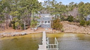 A lakeside property with a dock leading to a house surrounded by trees. - Port Peninsula Waterfront Paradise - Waterfront with Dock & Boat Lift (Oriental)