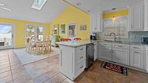 A kitchen with white cabinets, a yellow accent wall, and a dining area with chairs. - Port Peninsula Waterfront Paradise - Waterfront with Dock & Boat Lift (Oriental)