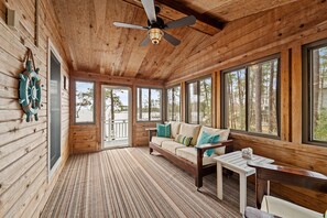 A wooden cabin interior with a sofa, a table, and a ceiling fan.