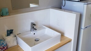 A modern bathroom with a white sink, a mirror above it, a microwave, and a refrigerator. - Mr.KINJO Happiness Resort 1 (Miyakojima)