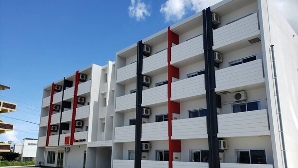 A multi-story building with white exterior walls, red accents, and air conditioning units. - Mr.KINJO Happiness Resort 1 (Miyakojima)