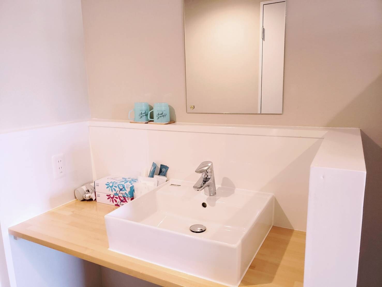Un baño con un lavabo blanco, un espejo encima y una encimera de madera.
