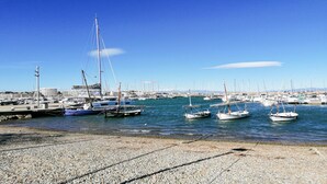 A marina with several sailboats docked, a pebbled beach, and a clear blue sky. - VACAY L'Escala – Gala Duplex with Pool and Parking near Riells Beach (l'Escala)