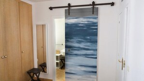 A hallway with a wooden wardrobe, a mirror, and a sliding door with a blue ocean mural. - VACAY L'Escala – Gala Duplex with Pool and Parking near Riells Beach (l'Escala)