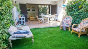 Une terrasse avec une table à manger, des chaises, un canapé et un fauteuil en osier.
