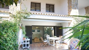 A patio with a table and chairs, a small cabinet, and a potted plant. - VACAY L'Escala – Gala Duplex with Pool and Parking near Riells Beach (l'Escala)