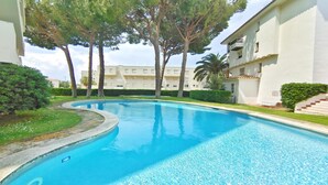 A swimming pool surrounded by greenery and a multi-story building with balconies. - VACAY L'Escala – Gala Duplex with Pool and Parking near Riells Beach (l'Escala)