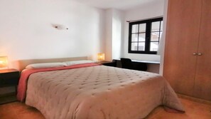 Une chambre à coucher comprenant un lit, des lampes de chevet, un bureau et une armoire.