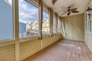 Una habitación con ventanas amplias, ventilador de techo y piso de madera.
