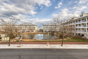A waterfront hotel with multiple balconies, a pond, and a pedestrian path. - Sunset Island 13 Fountain Drive West (Ocean City)