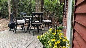 A wooden deck with outdoor furniture and a planter with yellow flowers. - Mtn Rd Cottage -HOT TUB-Close 2 Camelback/Shopping (Tannersville)