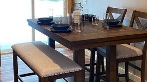 A dining area with a wooden table set for four, benches, and a view of greenery outside. - Mtn Rd Cottage -HOT TUB-Close 2 Camelback/Shopping (Tannersville)
