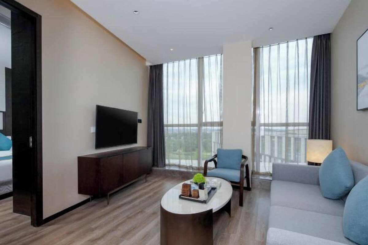 Habitació d'hotel moderna amb televisió de pantalla plana, un sofà, una cadira i una taula de cafè.