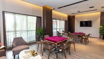 Habitación de hotel moderna con zona de comedor, ventanas amplias y televisión de pantalla plana.