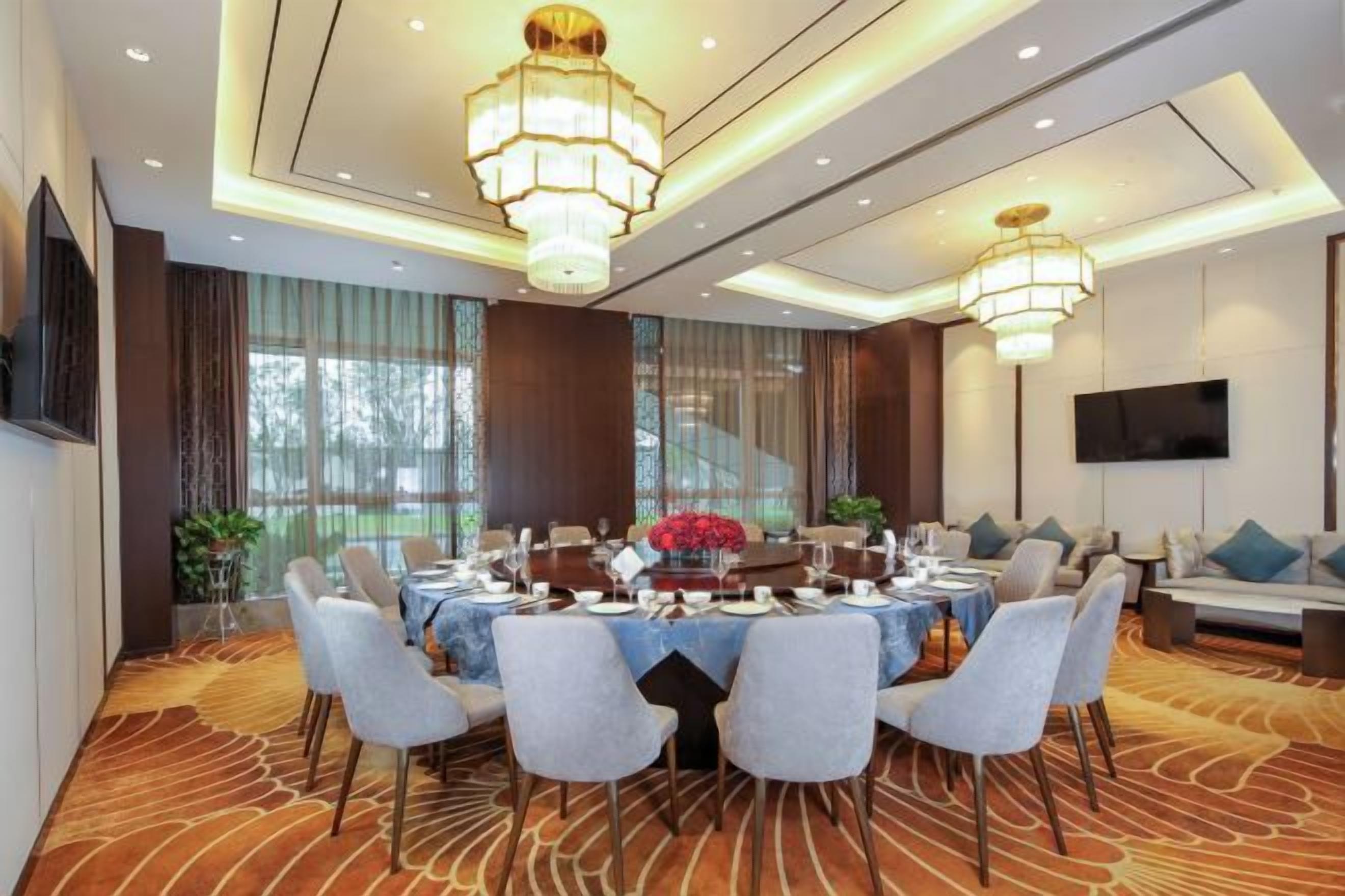 A conference room with a round table, chairs, and a chandelier.