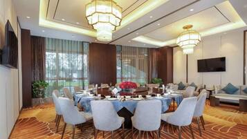 A conference room with a round table, chairs, and a chandelier.