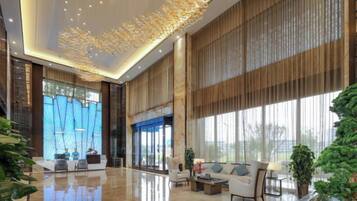 A spacious lobby with a high ceiling, large windows, and a modern chandelier.