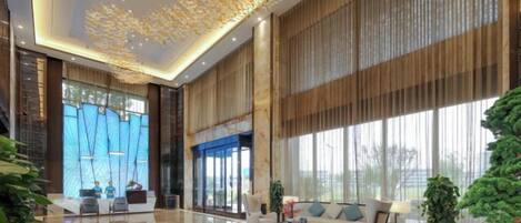 A spacious lobby with a high ceiling, large windows, and a modern chandelier.
