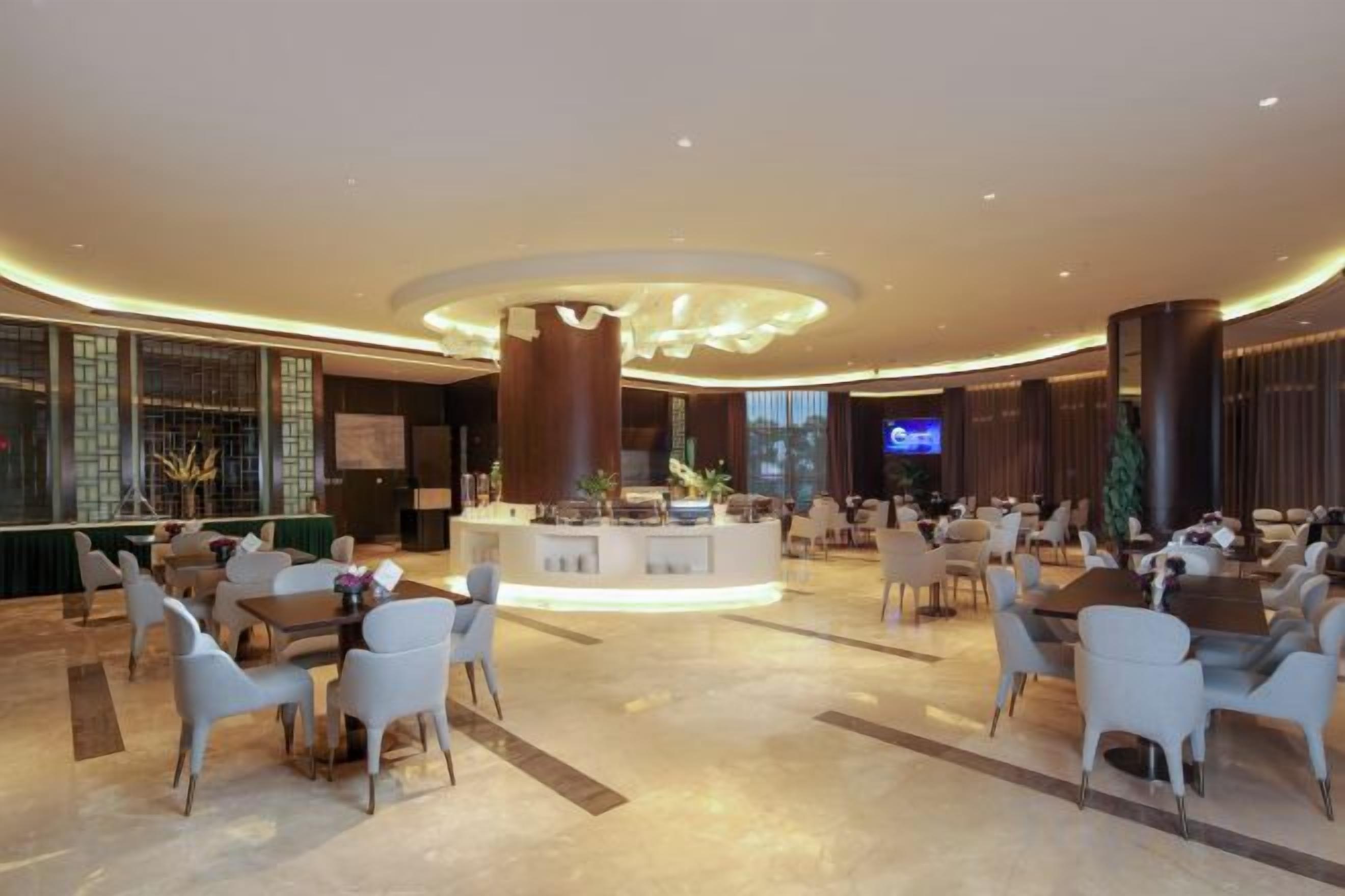 A spacious lobby with a central island, seating arrangements, and a television screen.