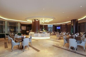 A spacious lobby with a central island, seating arrangements, and a television screen.