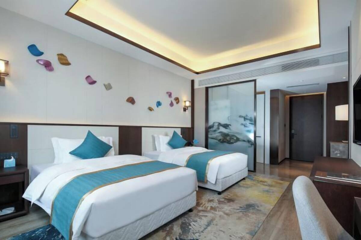 Habitació d'hotel amb dos llits, una finestra gran i un quadre a la paret.