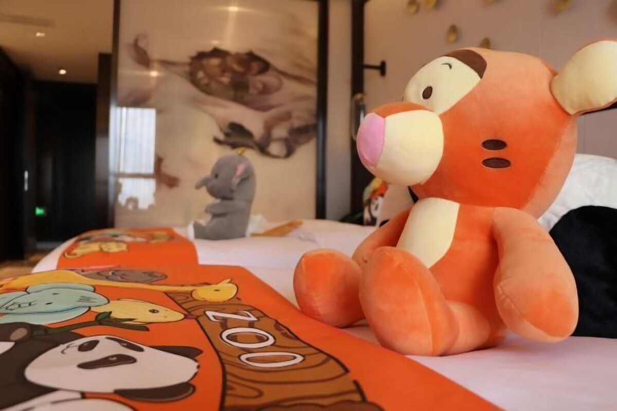 Un peluche sobre una cama con una colcha colorida.