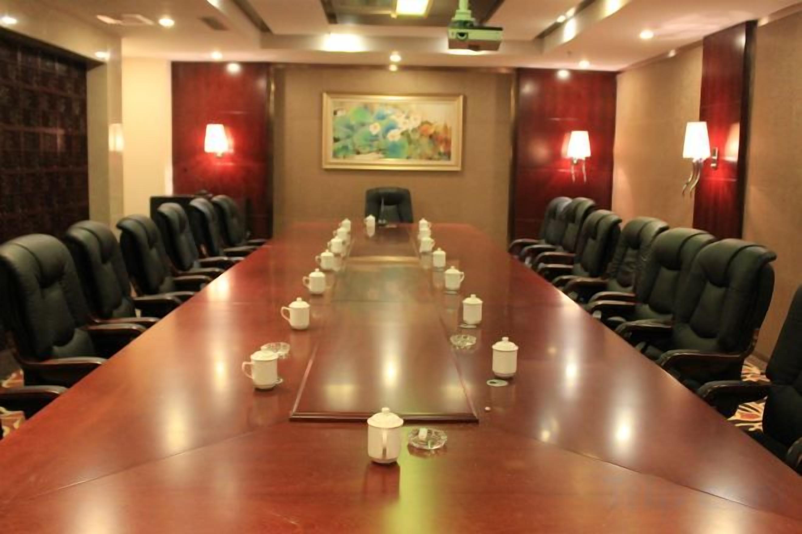 A conference room with a long table, chairs, and a projector screen.