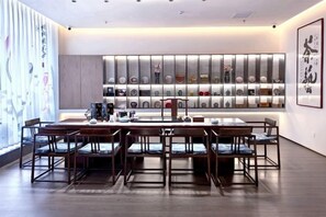 A modern dining area with a long table and chairs, a decorative wall with shelves, and a large framed artwork. - Xingya Mingdu Hotel (Jinzhong)